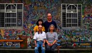 This picture taken on May 21, 2019 shows Hakka graffiti artist Wu Tsun-hsien (top R) posing with his family in front of their home in the Taiwanese village of Ruan Chiao. AFP /Sam Yeh