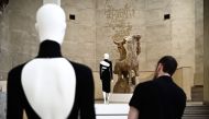 A man looks at a dress by Moroccan fashion designer Martine Sitbon (C) displayed next to a large plaster cast by French sculptor Antoine Bourdelle (1861-1929) at the off-site exhibition 'Back Side / Fashion from Behind' by the Palais Galliera held at the 