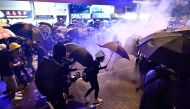 Protesters hold umbrellas as they are enveloped by tear gas on a street during a demonstration against a controversial extradition bill in Hong Kong on July 28, 2019. (AFP / Anthony WALLACE)