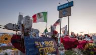 People pray and pay their respects at the makeshift memorial for victims of the shooting that left a total of 22 people dead at the Cielo Vista Mall WalMart (background) in El Paso, Texas, on August 6, 2019.AFP / Mark RALSTON