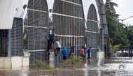 Youth climb up on the iron gates of a building submerged by floodwaters of the Kabini river at Nanjangudu in the Mysore district about 170 kms of the city of Bangalore on August 10, 2019.  AFP / STR