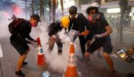 Anti-extradition bill protesters try to extinguish tear gas canisters during a demonstration in Wan Chai neighbourhood in Hong Kong, China, August 11, 2019. (REUTERS/Thomas Peter)