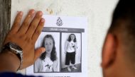 File photo of a police officer pasting a photo of 15-year-old Irish girl Nora Anne Quoirin who went missing from a resort on a wall at a shop in Seremban, Malaysia, August 9, 2019. REUTERS/Lim Huey Teng