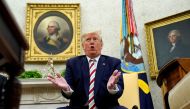 U.S. President Donald Trump answers questions while sitting in front of paintings of former U.S. presidents George Washington and Thomas Jefferson during his meeting with Romania's President Klaus Iohannis in the Oval Office of the White House in Washingt