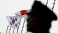 A police officer stands guard near Japan and South Korea national flags at hotel, where South Korean embassy in Japan is holding the reception to mark the 50th anniversary of normalisation of ties between Seoul and Tokyo, in Tokyo June 22, 2015. Reuters/T
