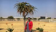 Mmaphuti Singo stands in front of some of the fauna planted through the Nasrec Memorial Park in Soweto, Johannesburg, South Africa, where she buried her husband last year, August 8 2019. Thomson Reuters Foundation/Kim Harrisberg.