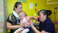  In this file photo taken on April 20, 2013 14-month-old Amelia Down sits on the lap of her mother Helen (L) as she receives the combined Measles Mumps and Rubella (MMR) vaccination at an MMR drop-in clinic at Neath Port Talbot Hospital near Swansea in so