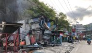 Residents ride motorcycles next to torched shops in Jayapura on August 30, 2019. AFP / BRAM
