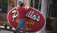 A worker removes a sign from the front of a restaurant as Hurricane Dorian continues to make its way toward the Florida coast on September 1, 2019 in Indialantic, Florida. Scott Olson/Getty Images/AFP