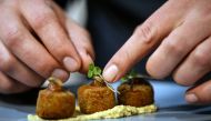 Chef Mario Barnard places coriander on croquettes made with Hermetia illucens (Black soldier fly larvae) flour and chickpea flour served on a bed of mopane worm tahini hummus at the Insect Experience Restaurant in Cape Town, South Africa, August 23, 2019.