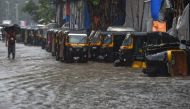 A pedestrian wades through a waterlogged street next to a line of auto rickshaws in heavy rain in Mumbai on September 4, 2019. / AFP / PUNIT PARANJPE