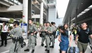 Passengers roll their luggage past police outside Chek Lap Kok International Airport in Hong Kong on September 7, 2019. AFP / Anthony Wallace 
