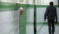 (FILES) In this file photo taken on June 13, 2006 an Iranian inmate peers from behind a wall as a guard walks by at the female section of the infamous Evin jail, north of Tehran. AFP / ATTA KENARE