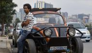 Ethiopian painter Robel Wolde, 25, poses in front of his Volkswagen Beetle during an interview with AFP, in Addis Ababa on September 2, 2019. AFP / Michael Tewelde