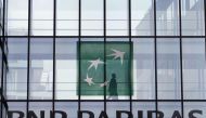 An employee walks behind the logo of BNP Paribas in a company's building in Issy-les-Moulineaux, near Paris, June 2, 2014. Reuters/Charles Platiau 