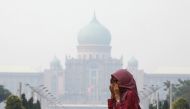 A woman covers her face with a scarf in front of the Malaysia's Prime Minister's office, which is shrouded in haze, in Putrajaya, Malaysia, September 17, 2019. REUTERS/Lim Huey Teng