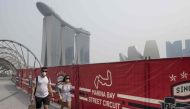 Tourists wear protective masks as they walk near the Formula One Singapore Grand Prix night race track while haze blankets Singapore on September 18, 2019. AFP / Mladen ANTONOV
