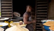 A Nigerian man poses next to some rice in his shop at Ajara Market in Badagry, near Lagos, on September 6, 2019.  AFP / Benson Ibeabuchi