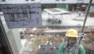 A multi-language sign, written the Thai, Cambodian and Myanmar languages, is seen as a construction labourer works at a building site in Bangkok June 18, 2014. Reuters/Athit Perawongmetha