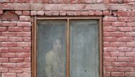 A Kashmiri woman looks out from a window of a house as protesters pass by, after Friday prayers during restrictions, following scrapping of the special constitutional status for Kashmir by the Indian government, in Srinagar, September 20, 2019. REUTERS/Fr