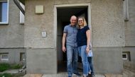 Carsten and Peggy Hoffmann pose outside their temporary flat in Glindenberg, near Magdeburg on August 16, 2019. AFP / John John MacDougall