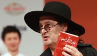 In this file photo taken on February 5, 2018 French chef Marc Veyrat, holds a Michelin guide after being awarded the maximum three Michelin stars, during the Michelin guide award ceremony at La Seine Musicale in Boulogne-Billancourt near Paris. / AFP / JA