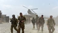 US soldiers walk as a NATO helicopter flies overhead in the Khogyani district in the Afghan eastern province of Nangarhar on August 12, 2015. AFP/Wakil Kohsar