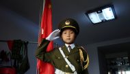 Feng Jianhan, 9, poses for a picture in military uniform next to a Chinese flag that he raises every morning through rope and pulley at his home in Xian, Shaanxi province, China September 26, 2019. Picture taken September 26, 2019. REUTERS/Irene Wang
