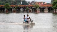 A man and a boy ride a scooter through a flooded road after heavy rains in Prayagraj, India, September 29, 2019. REUTERS/Jitendra Prakash
