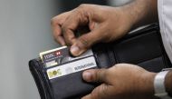 A man pulls out his credit card to make a purchase at a shop in Colombo June 11, 2013. Reuters/Dinuka Liyanawatte