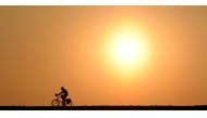 A cyclist passes a street near the village of Pflaumdorf, southern Germany, during sunset on February 28, 2019. AFP/Christof Stache