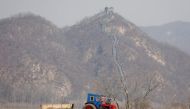 Farmers in a field as a section of the Great Wall is seen on the Chinese side of the Yalu River north of the town of Sinuiju in North Korea and Dandong in Chinese Liaoning province, April 2, 2017. Reuters / Damir Sagolj