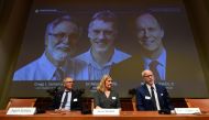 Nobel Assembly members (L-R) Patrik Ernfors, Anna Wedell and Randall Johnson sit in front of a screen displaying the winners of the 2019 Nobel Prize in Physiology or Medicine (L-R) Gregg Semenza, Peter Ratcliffe and William Kaelin after their names were a