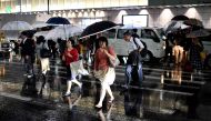 People use umbrellas to shelter from the rain as they cross a street next to the Shinjuku JR Tokyo Station on October 11, 2019. (AFP / FRANCK FIFE)