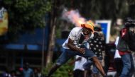 A protester runs for cover as police fire tear gas during a protest on the street to demand the resignation of the Haitian president in Port-au-Prince, Haiti on October 13, 2019. AFP / Chandan Khanna 