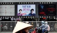 Bikers go past an empty space where a promotional poster for the DreamWorks film