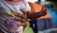 El Salvadoran asylum seeker Wendy, carries her eight-month-old daughter Pamela, in an encampment near the Gateway International Bridge where they have been living for about a month after they were sent back under the 