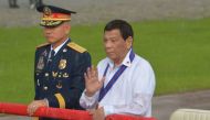 This file photo taken on August 8, 2018 shows Philippine President Rodrigo Duterte (R) reviewing policemen along with national police chief Oscar Albayalde (L) in a sudden downpour during the 117th police anniversary celebration at the national headquarte