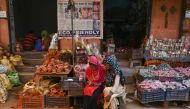 In this photograph taken on October 4, 2019, women use a mobile phone as they sit outside their shop displaying items made of clay, at Kumhar Gram (Potter's Village) in New Delhi. AFP / Money Sharma
 