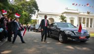Officials who work at the presidential palace wave Indonesian flags as President Joko Widodo's motorcade leaves the palace in Jakarta on October 20, 2019, to attend his inauguration as Indonesia's president for a second term. Widodo was to kick off a fres