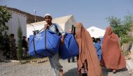 An Afghan family who were living as refugees in Pakistan carries bundles of supplies at a humanitarian aid station in Torkham, Afghanistan, October 22, 2016. Reuters / Josh Smith