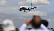 Visitors watch as a Boeing 737 Max lands after an air display during the Farnborough Airshow south west of London on July 16, 2018. AFP / Ben Stansall