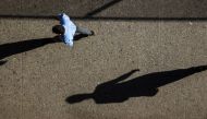 The morning sun casts long shadows as commuters walk along a sidewalk in New York August 28, 2015. Reuters/Lucas Jackson