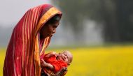 A woman holds a baby as she walks through a mustard field on the outskirts of Dhaka January 22, 2014. Reuters/Andrew Biraj 