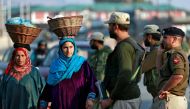 Kashmiri women walk past Indian policemen standing guard in a street in Srinagar October 31, 2019. Reuters/Danish Ismail