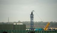 (FILES) In this file photo taken on October 16, 2018 cows graze in a field as work gets under way at the Preston New Road drill site where energy firm Cuadrilla Resources have commenced fracking (hydraulic fracturing) operations to extract shale gas, near