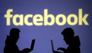 Silhouettes of laptop users are seen next to a screen projection of Facebook logo in this picture illustration taken March 28, 2018. Reuters / Dado Ruvic