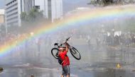 A demonstrator lifts his bike in the air during clashes with riot police in Santiago on October 24, 2019. AFP / Martin Bernetti