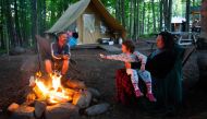 A family enjoys a campfire at the Huttopia Sutton glamping ground in Quebec, Canada, on August 14, 2019. AFP / Sebastien St-Jean