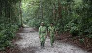 Two forest rangers walk on a road in the Akanda forest, a national park a few kilometers from the city centre of the capital, Libreville on September 27, 2019. AFP / Steve Jordan